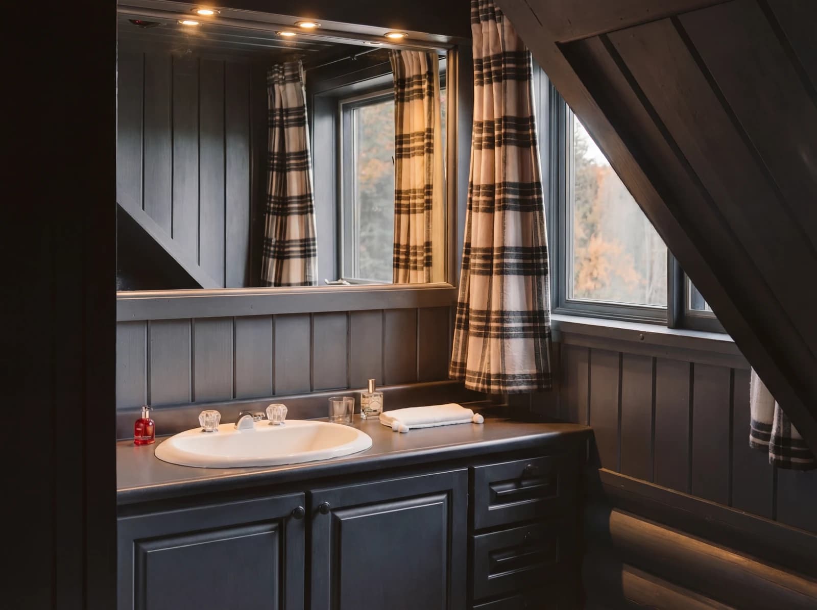 Bathroom vanity with mirror under angled ceiling