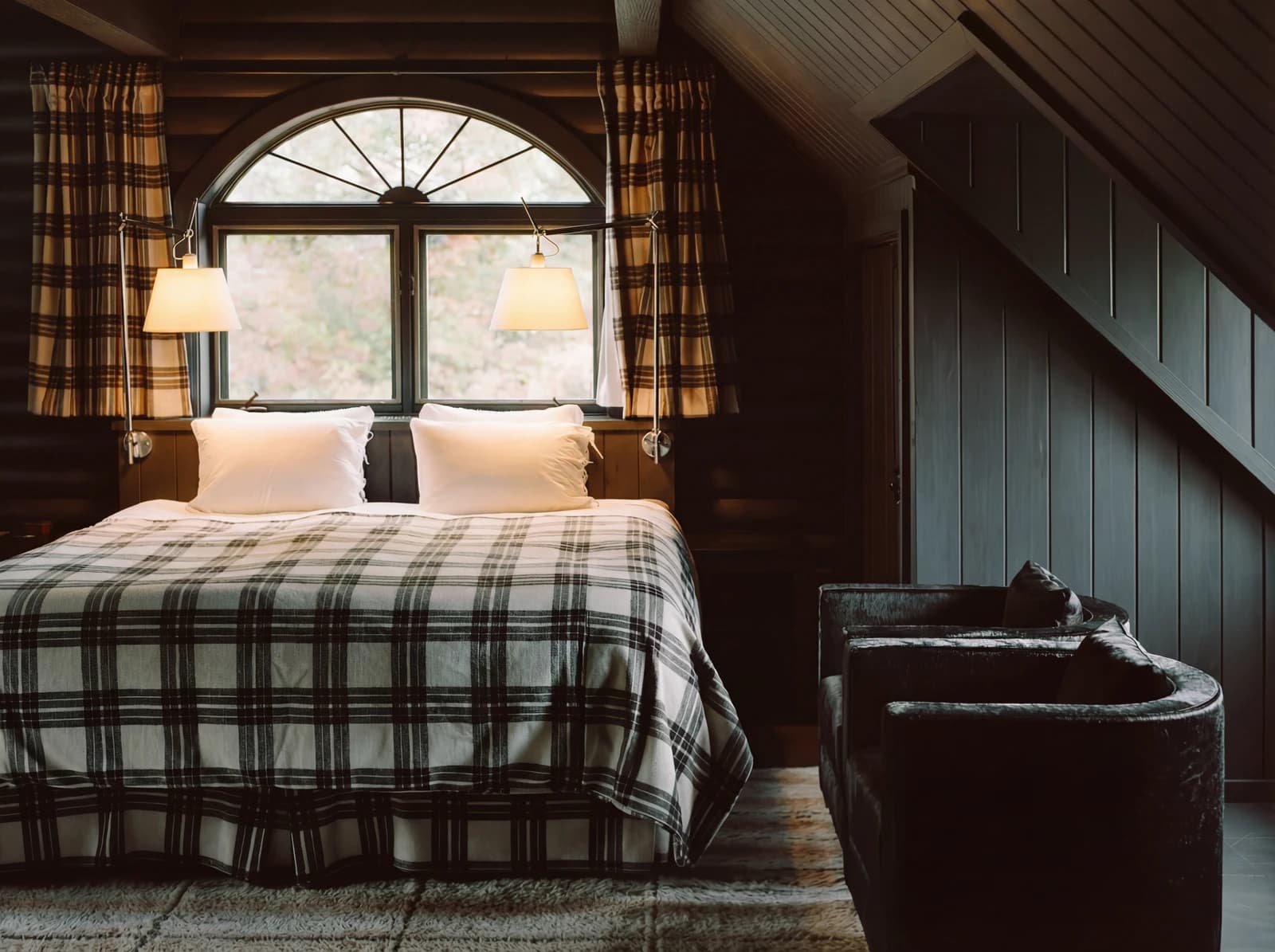 Upper bedroom with arched window and plaid bedding