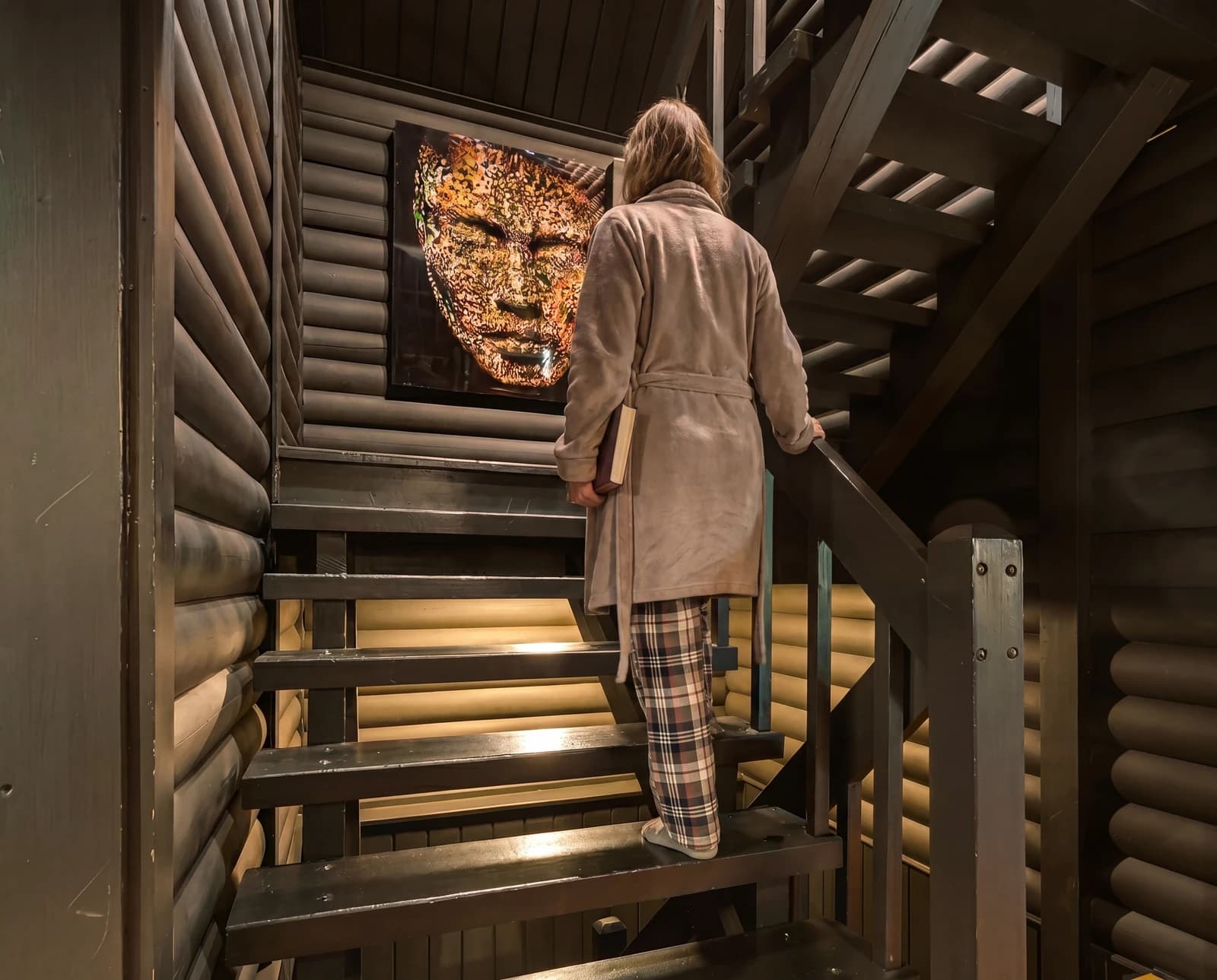 Woman in robe ascending lit staircase with artwork