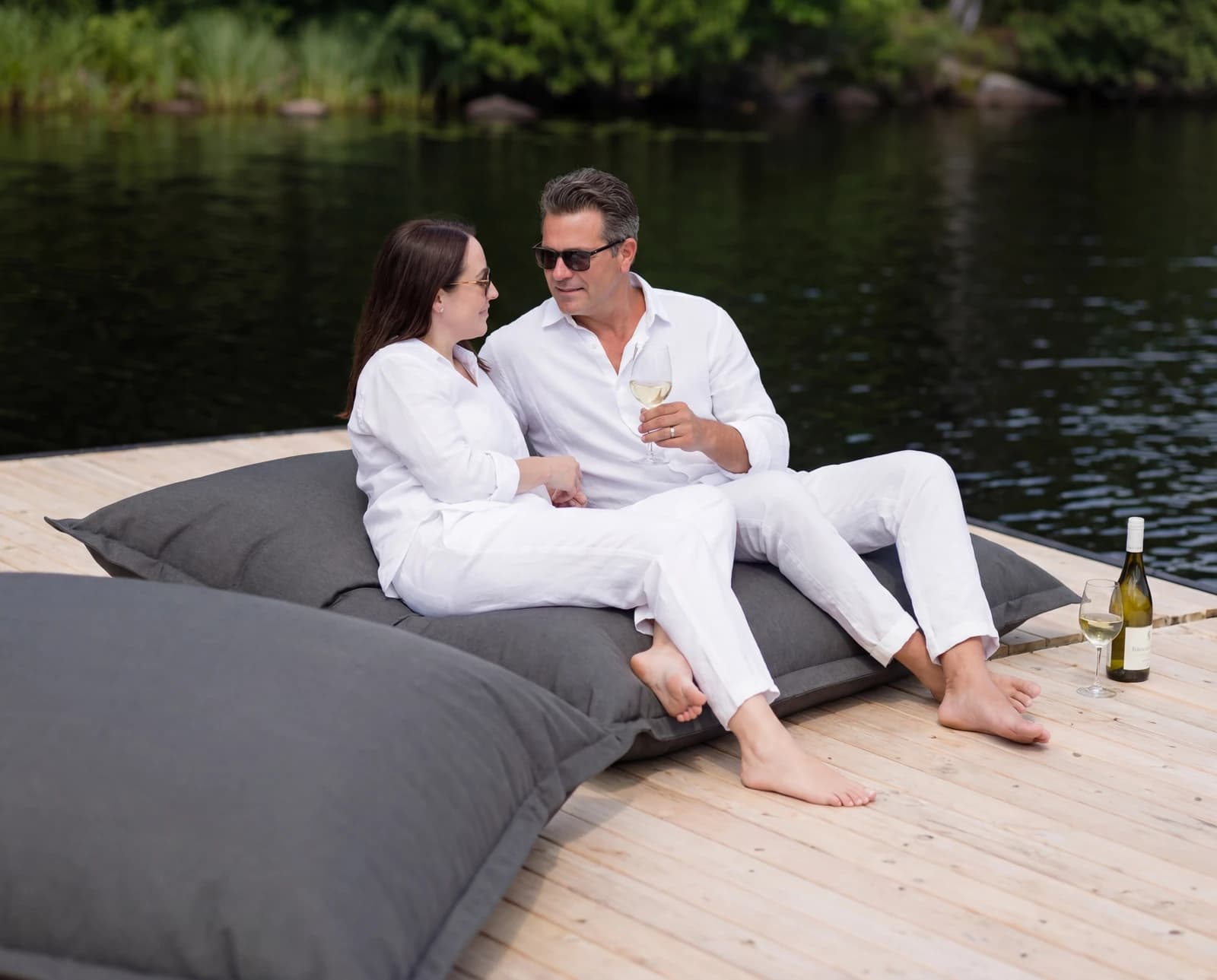 Couple relaxing on a lakeside daybed with wine