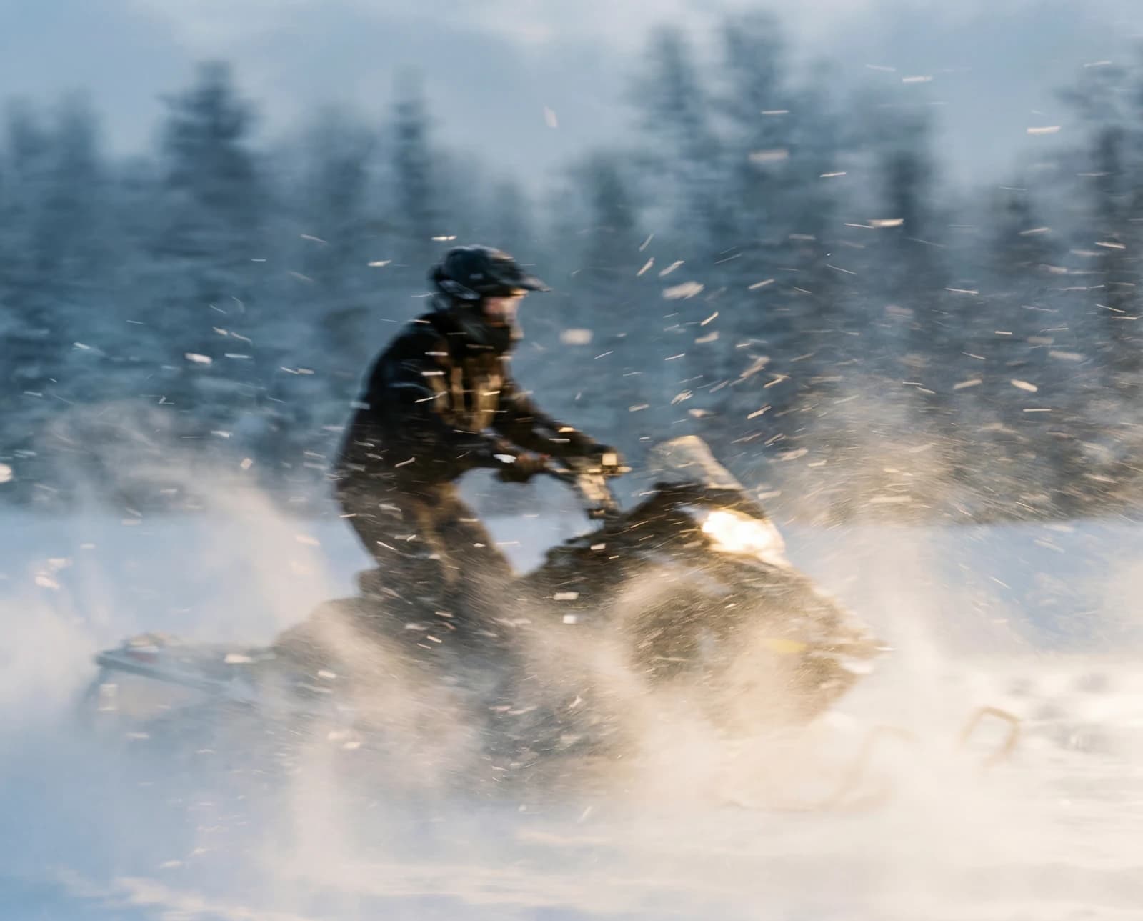 Snowmobile throwing up snow on the trail
